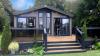 Outside View of a Luxury Lodge with a Decking area surrounded by Trees